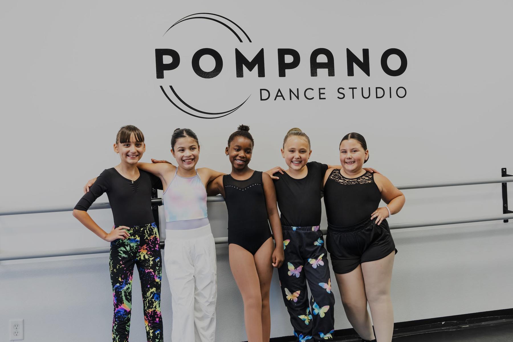 Dancers together under the Pompano Dance Studio wall mark