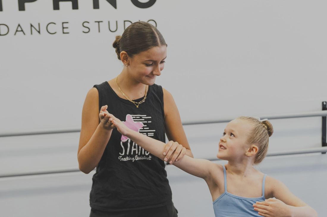 A teacher guiding a young dancer at Pompano Dance Studio